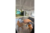 2024 Nimbus 305 Coupe interior with wooden table, chairs, and cushioned seating.