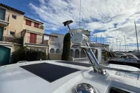 2024 Nimbus 305 Coupe yacht docked near colorful waterfront buildings under a partly cloudy sky.