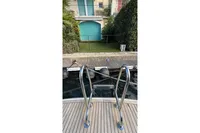 Stainless steel boat ladder on 2024 Nimbus 305 Coupe docked by a waterfront home.