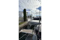 2024 Nimbus 305 Coupe docked near waterfront villa under cloudy sky.