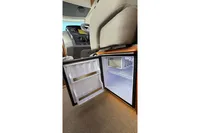 Open mini fridge inside 2024 Nimbus 305 Coupe, showcasing interior storage space.