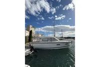 2024 Nimbus 305 Coupe yacht docked in a sunny marina, under a partly cloudy sky.