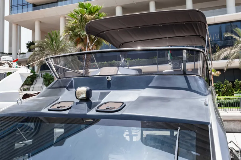 Yacht Photos Pics 2019 Cranchi E 52F yacht with sleek design, docked near modern building and palm trees.