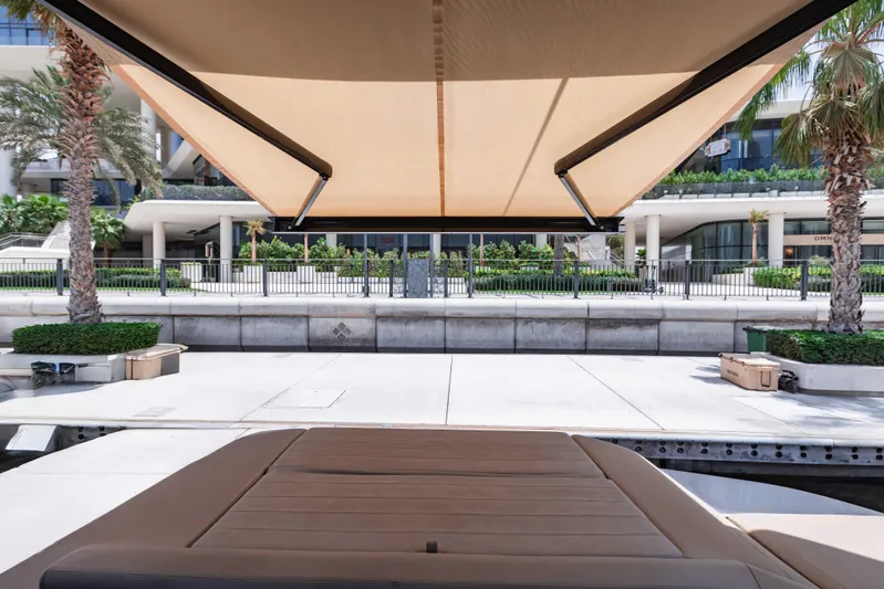  Yacht Photos Pics 2019 Cranchi E 52F yacht with sunshade, docked near modern waterfront buildings.