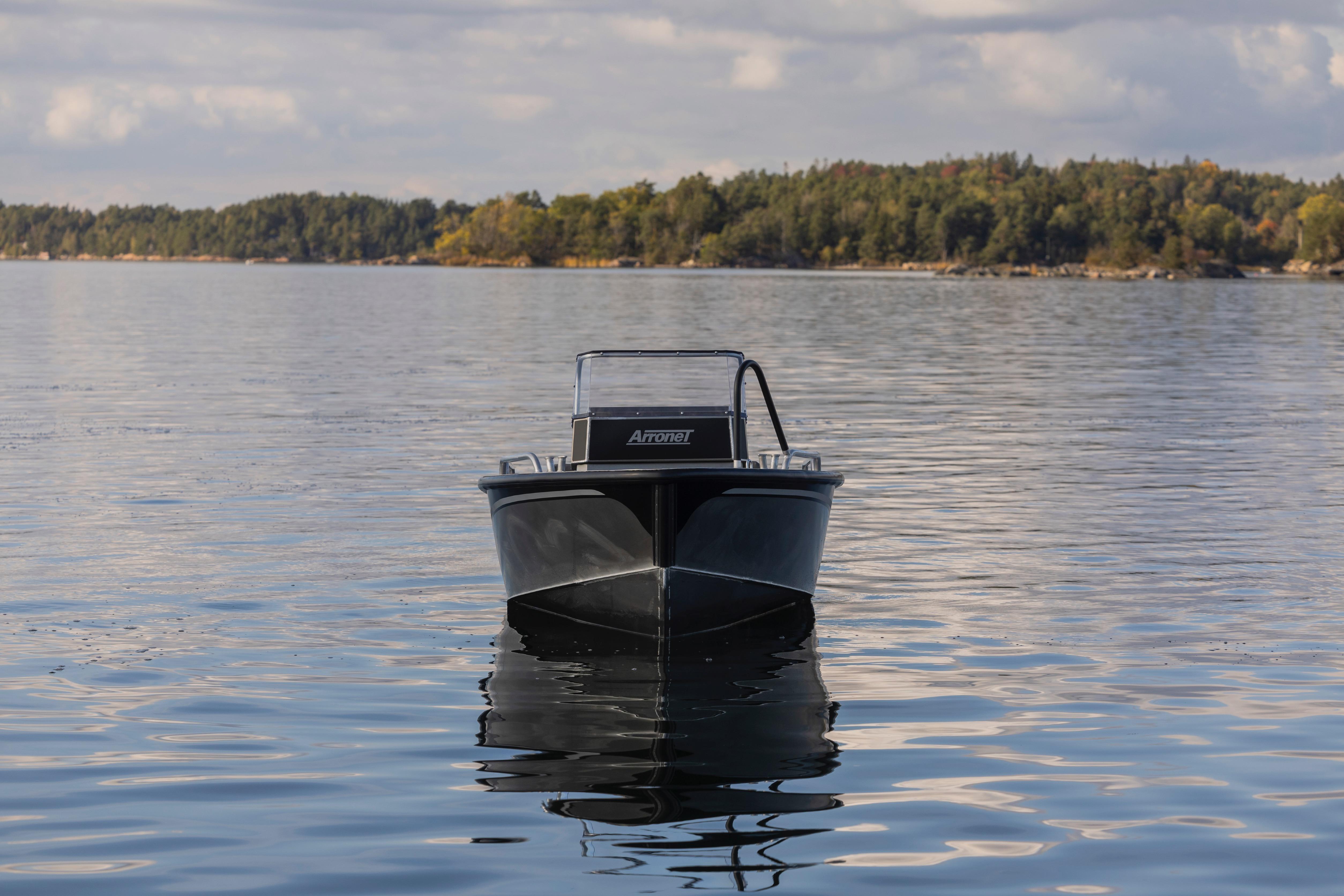 2025 Arronet 18 SP boat on calm water with forested shoreline in the background.