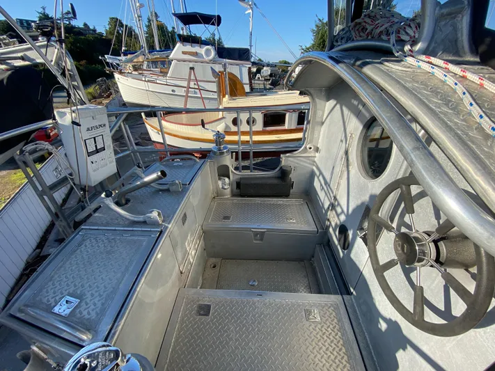 Silverado Yacht Photos Pics 2009 Custom Pilothouse Cutter cockpit with steering wheel and metal deck, docked near other boats.