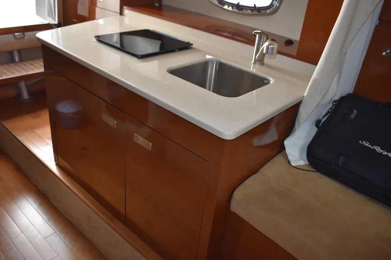 Windy Gale IV Yacht Photos Pics 2011 Sea Ray 310 Sundancer interior with kitchenette, sink, and wooden cabinetry.