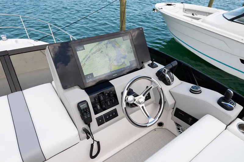  Yacht Photos Pics Manufacturer Provided Image: 2025 Regal 38 FXO helm with navigation display and steering wheel, docked by the water.