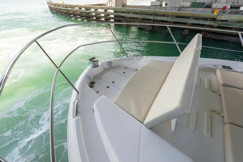  Yacht Photos Pics Manufacturer Provided Image: 2025 Regal 38 FXO boat with sleek seating, cruising on turquoise waters near a wooden dock.