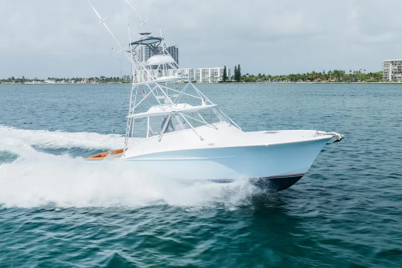Attitudes Yacht Photos Pics 2019 Custom Carolina Daniels Boatworks cruising on open water, with coastal buildings in the background.