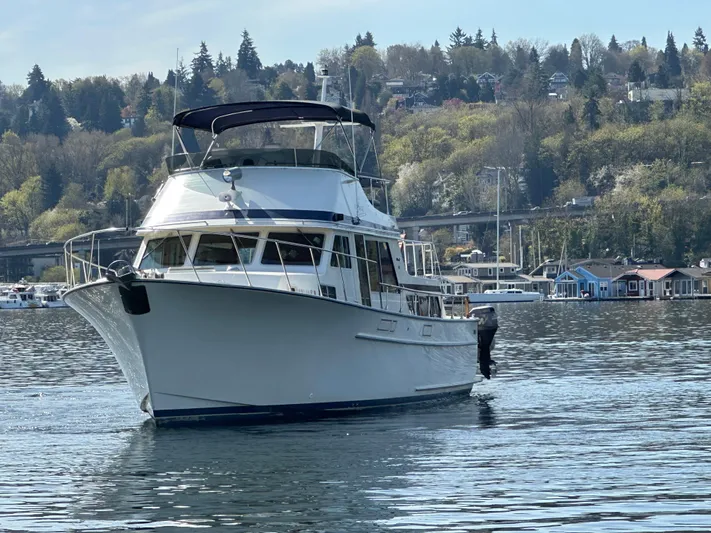  Yacht Photos Pics 1982 Tollycraft Tri Cabin boat on a serene lake with forested hills in the background.