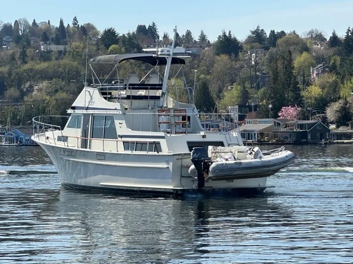 Yacht Photos Pics 1982 Tollycraft Tri Cabin yacht on a serene lake with scenic background.