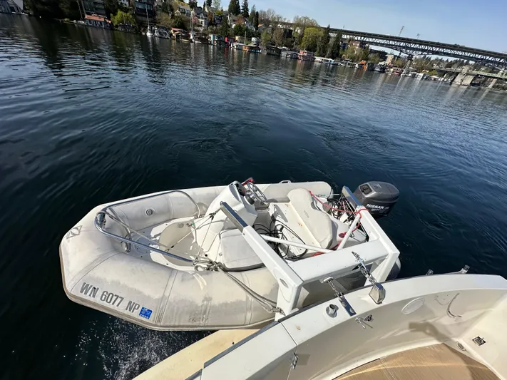  Yacht Photos Pics 1982 Tollycraft Tri Cabin with inflatable dinghy on calm water near a bridge.
