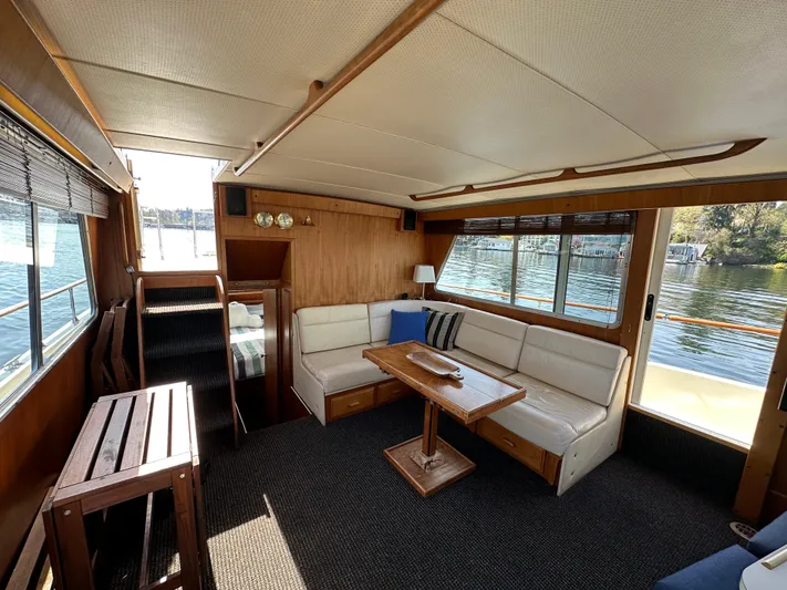  Yacht Photos Pics 1982 Tollycraft Tri Cabin interior with cozy seating, wooden table, and large windows overlooking water.