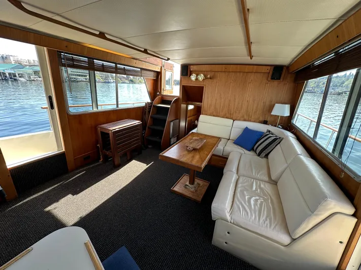  Yacht Photos Pics 1982 Tollycraft Tri Cabin interior with white leather seating, wooden table, and waterfront view.