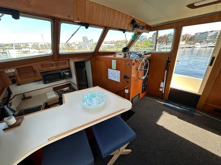  Yacht Photos Pics 1982 Tollycraft Tri Cabin interior with helm, dining area, and waterfront view.