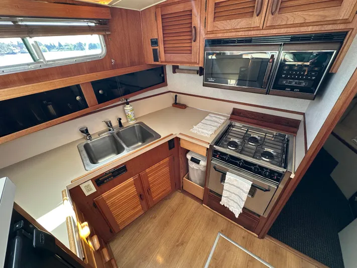  Yacht Photos Pics 1982 Tollycraft Tri Cabin kitchen with stove, sink, and wooden cabinetry.