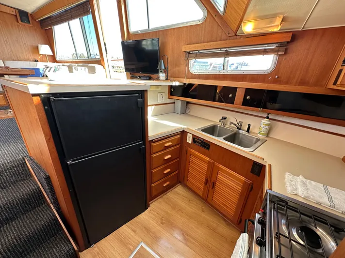  Yacht Photos Pics 1982 Tollycraft Tri Cabin kitchen with wood cabinetry, black fridge, and dual sink.