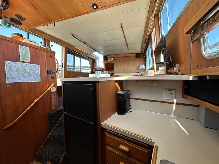  Yacht Photos Pics 1982 Tollycraft Tri Cabin interior with kitchenette, wooden cabinetry, and natural light.