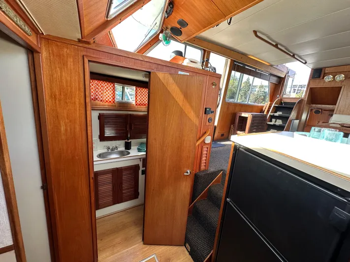 Yacht Photos Pics 1982 Tollycraft Tri Cabin interior with wood paneling, kitchenette, and natural light.