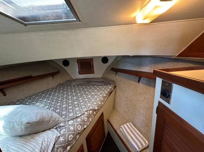  Yacht Photos Pics 1982 Tollycraft Tri Cabin interior with cozy bed, wooden accents, and soft lighting.