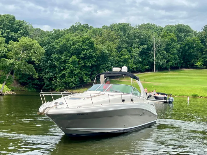  Yacht Photos Pics 2006 Sea Ray 340 Sundancer cruising on a serene lake with lush green forest backdrop.