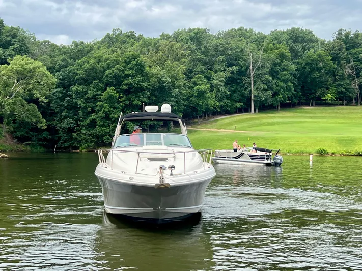  Yacht Photos Pics 2006 Sea Ray 340 Sundancer cruising on a serene lake with lush green forest backdrop.