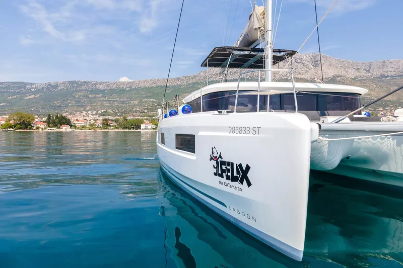  Yacht Photos Pics 2024 Lagoon 450 F catamaran on serene water with scenic mountain backdrop.