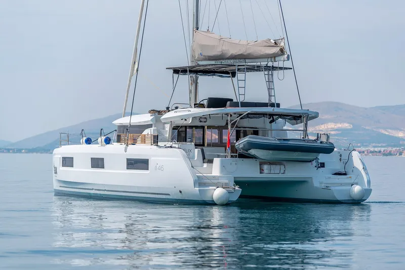  Yacht Photos Pics 2024 Lagoon 450 F catamaran on calm water with scenic mountain backdrop.