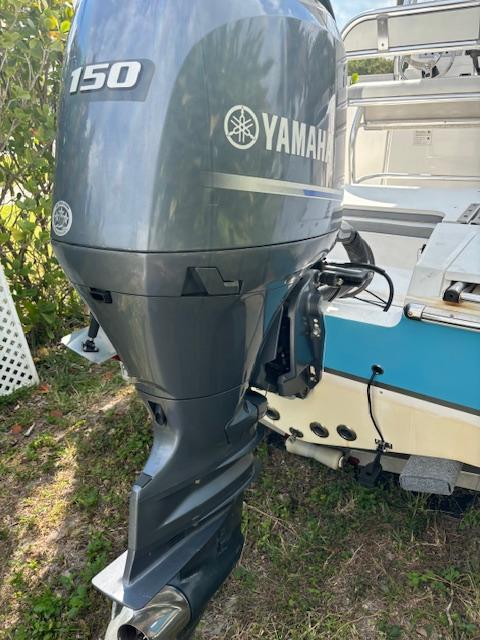 Yamaha 150 outboard motor on 2016 Release 208 RX boat, parked on grass.