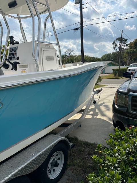 2016 Release 208 RX boat on trailer, parked beside a black vehicle, under a partly cloudy sky.