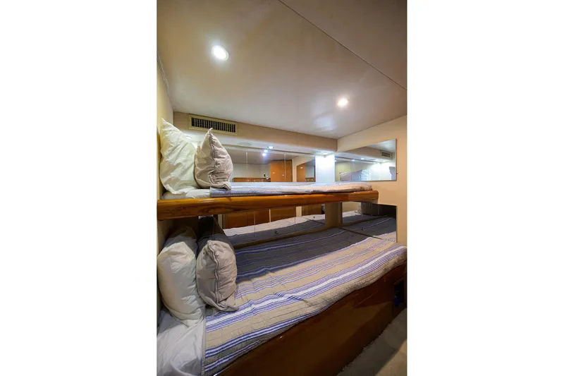Fine Expierence Yacht Photos Pics Bunk beds in 2001 Viking 65 Enclosed Bridge yacht cabin, featuring cozy bedding and ambient lighting.