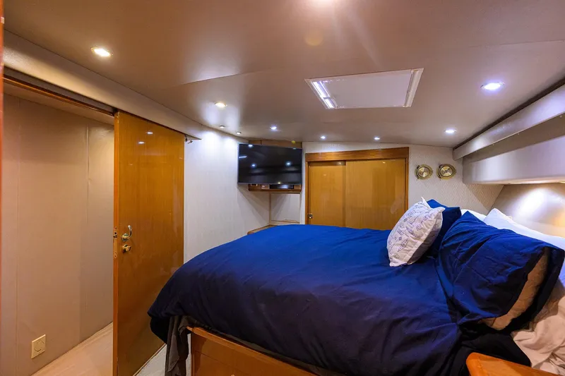 Fine Expierence Yacht Photos Pics Luxurious bedroom interior of 2001 Viking 65 Enclosed Bridge yacht with blue bedding and TV.