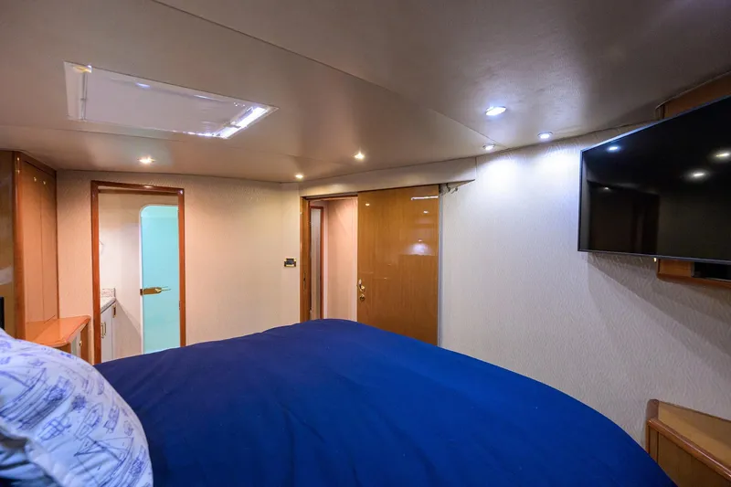 Fine Expierence Yacht Photos Pics Interior of 2001 Viking 65 Enclosed Bridge yacht bedroom with TV and blue bedding.