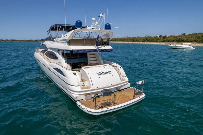Shhmic Yacht Photos Pics 2001 Sunseeker Manhattan 74 yacht on blue water near a sandy shore.