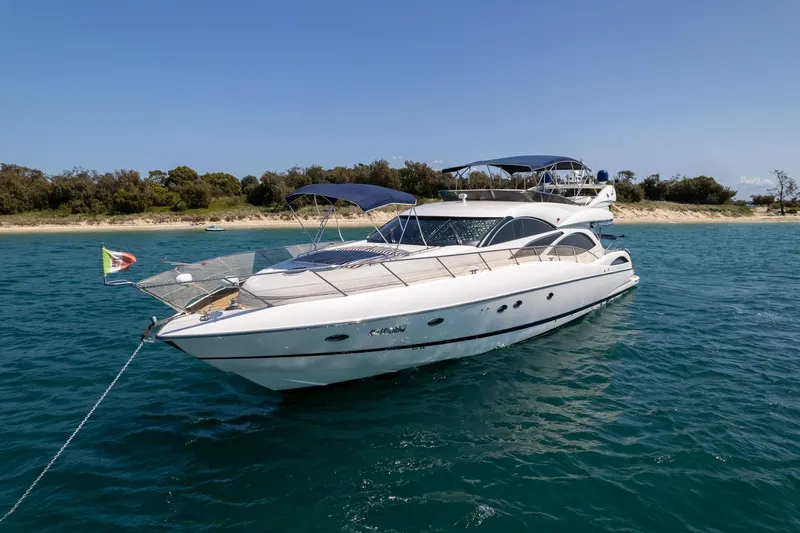 Shhmic Yacht Photos Pics 2001 Sunseeker Manhattan 74 yacht anchored in clear blue water near a sandy shoreline.