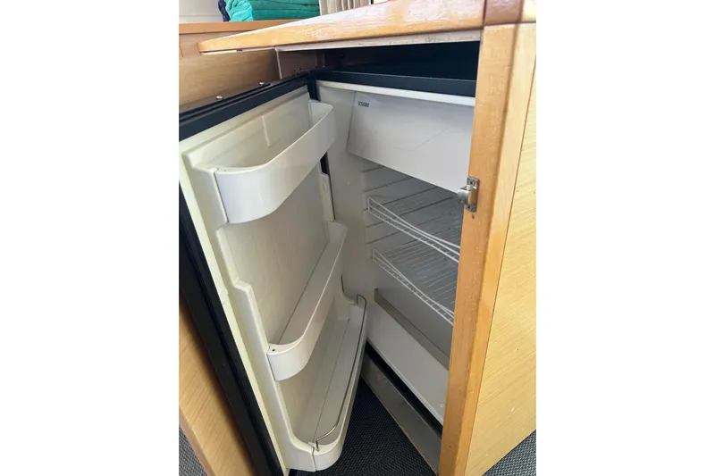  Yacht Photos Pics Open refrigerator inside a 2012 Lagoon 450 yacht, showcasing empty shelves and door compartments.