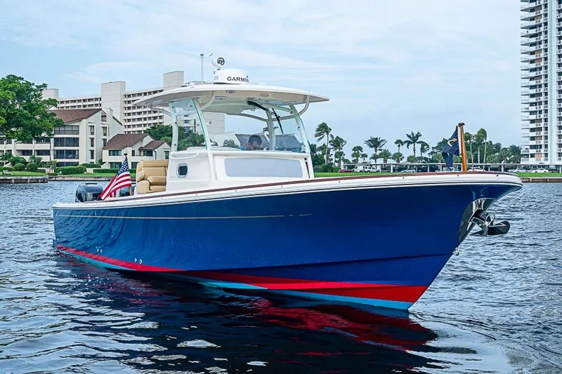 Blue Streak Yacht Photos Pics 2018 Hunt Yachts 32 Center Console on water, blue hull, American flag, urban backdrop.