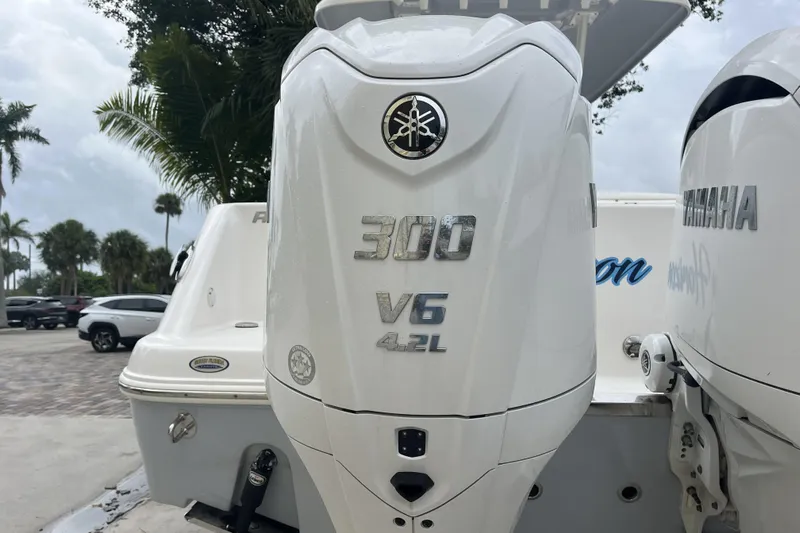 300 - 112 Brokerage Kevin Yacht Photos Pics 2023 Robalo R302 Center Console with Yamaha 300 V6 outboard engine, parked near palm trees.