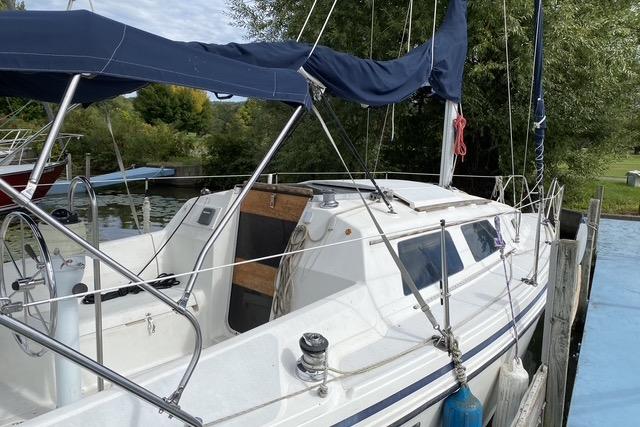 1990 Hunter 27 sailboat docked, featuring a blue canopy and white hull.