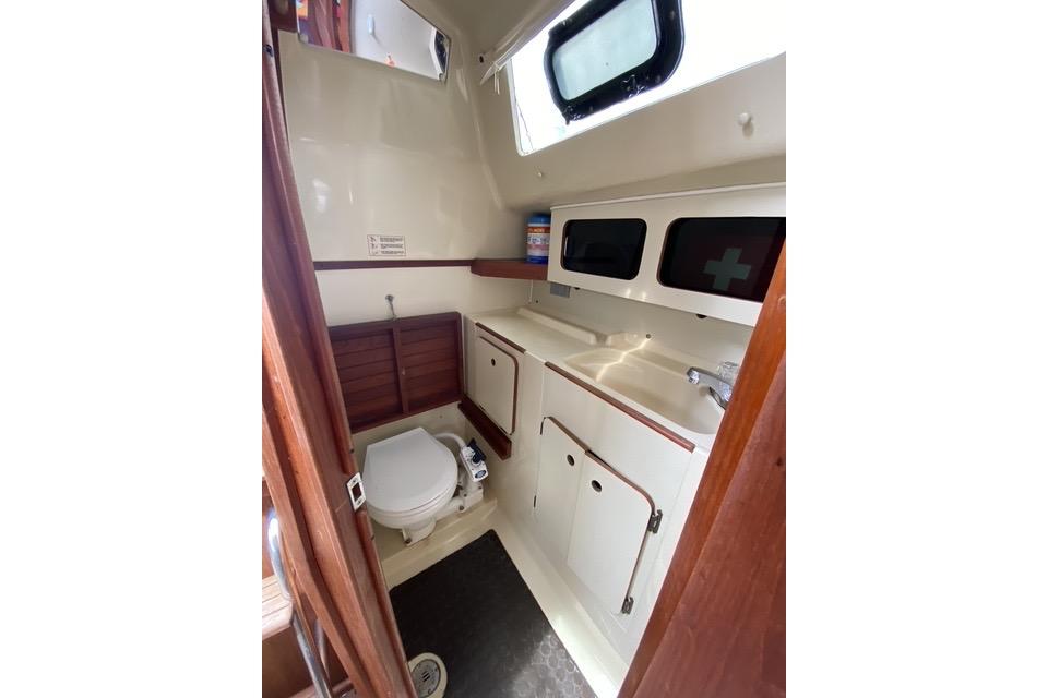 1990 Hunter 27 sailboat bathroom with toilet, sink, and storage cabinets.