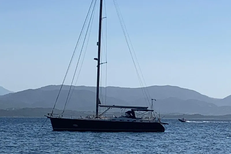  Yacht Photos Pics Sailing yacht Beneteau Oceanis Clipper 523, 2004 model, on calm sea with mountainous backdrop.