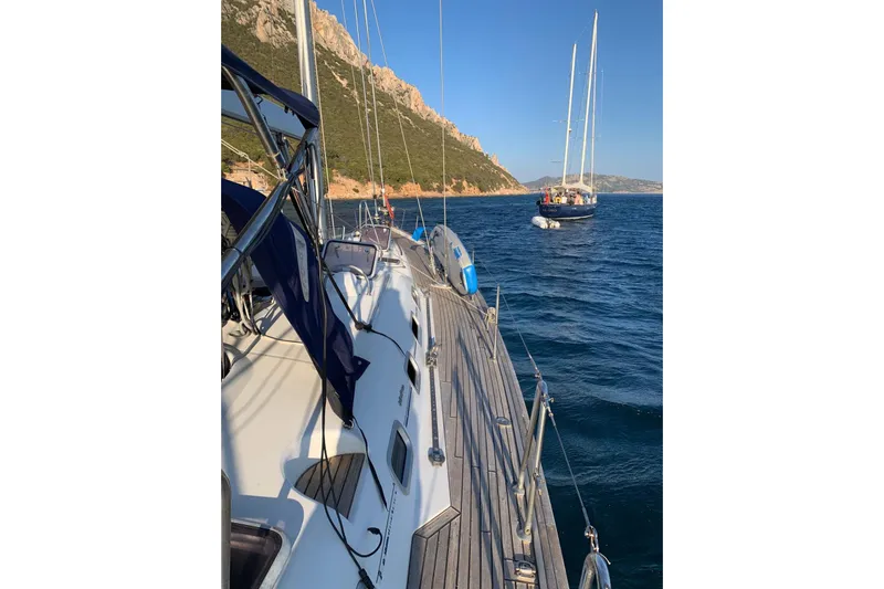  Yacht Photos Pics 2004 Beneteau Oceanis Clipper 523 sailing near rocky coastline under clear blue sky.