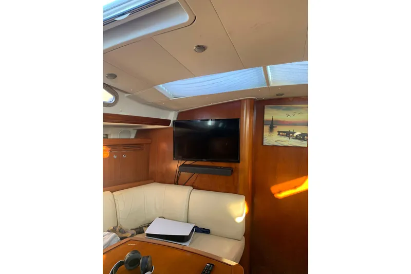 Yacht Photos Pics Interior of 2004 Beneteau Oceanis Clipper 523 with TV, sofa, and wall art.