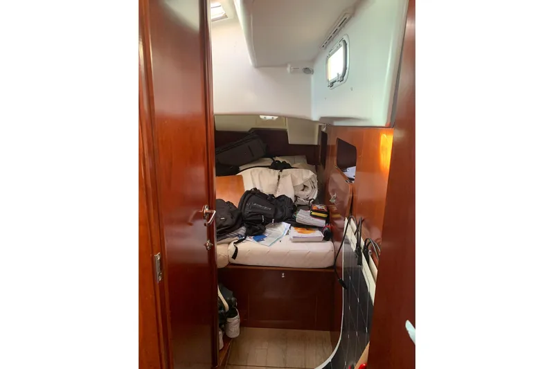  Yacht Photos Pics Interior cabin of 2004 Beneteau Oceanis Clipper 523 with cluttered bed and wooden finish.