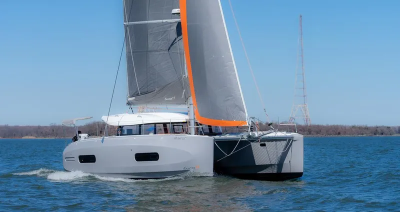 Eli X Yacht Photos Pics 2023 Excess 11 catamaran sailing on open water with gray and orange sails.