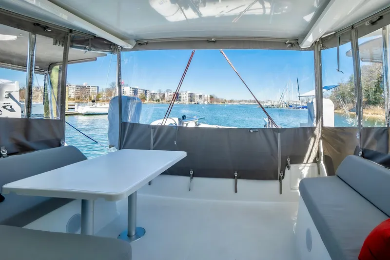 Eli X Yacht Photos Pics Interior view of 2023 Excess 11 catamaran with seating and table, overlooking marina.