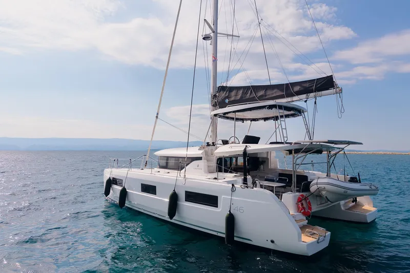 Almissa Yacht Photos Pics 2023 Lagoon 46 catamaran sailing on open sea under clear skies.