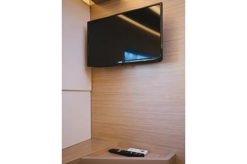 Almissa Yacht Photos Pics Wall-mounted TV and remote in a modern interior of 2023 Lagoon 46 yacht.