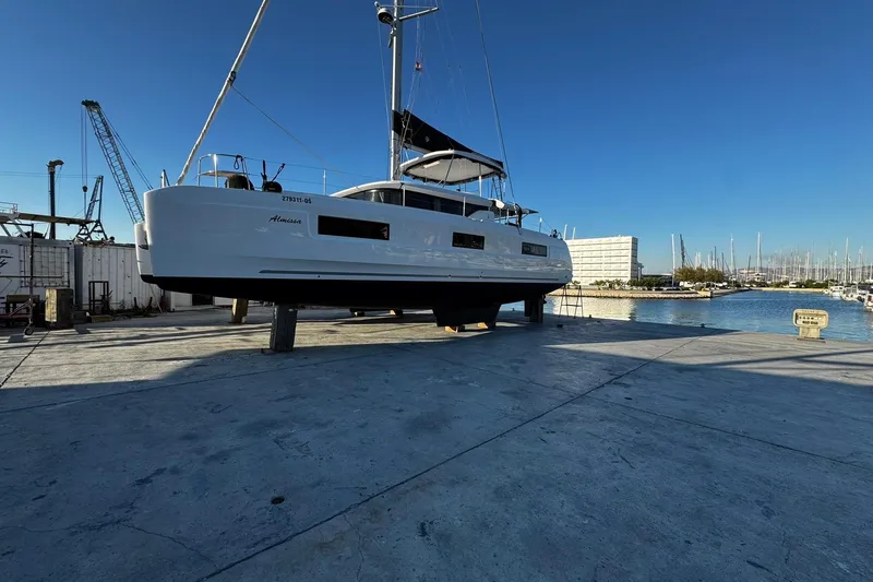 Almissa Yacht Photos Pics 2023 Lagoon 46 catamaran on dry dock near marina, clear blue sky.